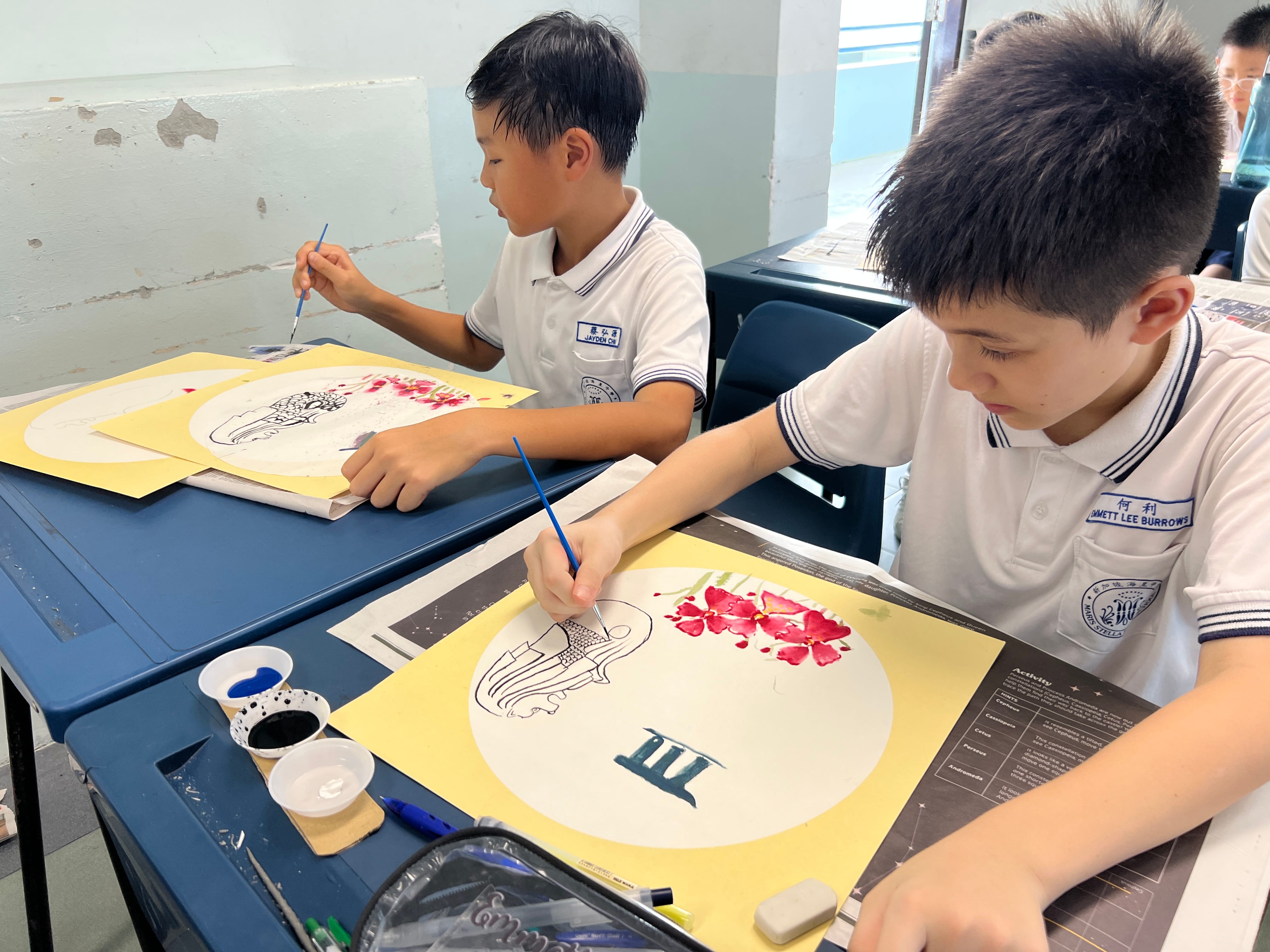 Students in white uniforms and face masks view framed colorful artwork displayed on a decorated wall.